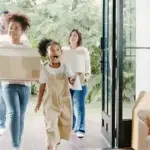 Joyful family carrying boxes as they move into a sunny home