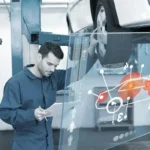 Mechanic in blue coveralls reviews a paper beside a car on a lift, with a translucent holographic car diagram in view.