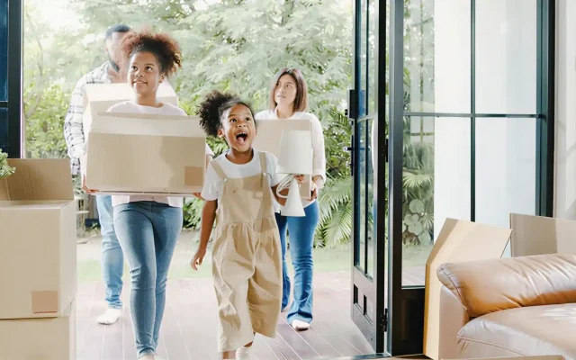 Joyful family carrying boxes as they move into a sunny home