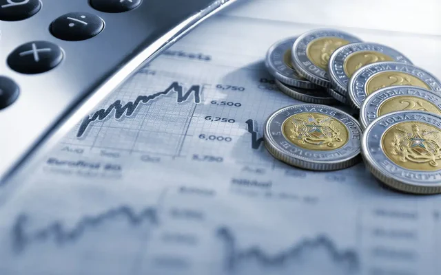 Calculator beside a financial chart and a pile of coins, symbolizing money and market analysis.
